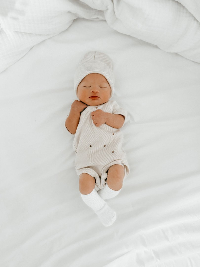 Newborn Olli sleeping on white bedding